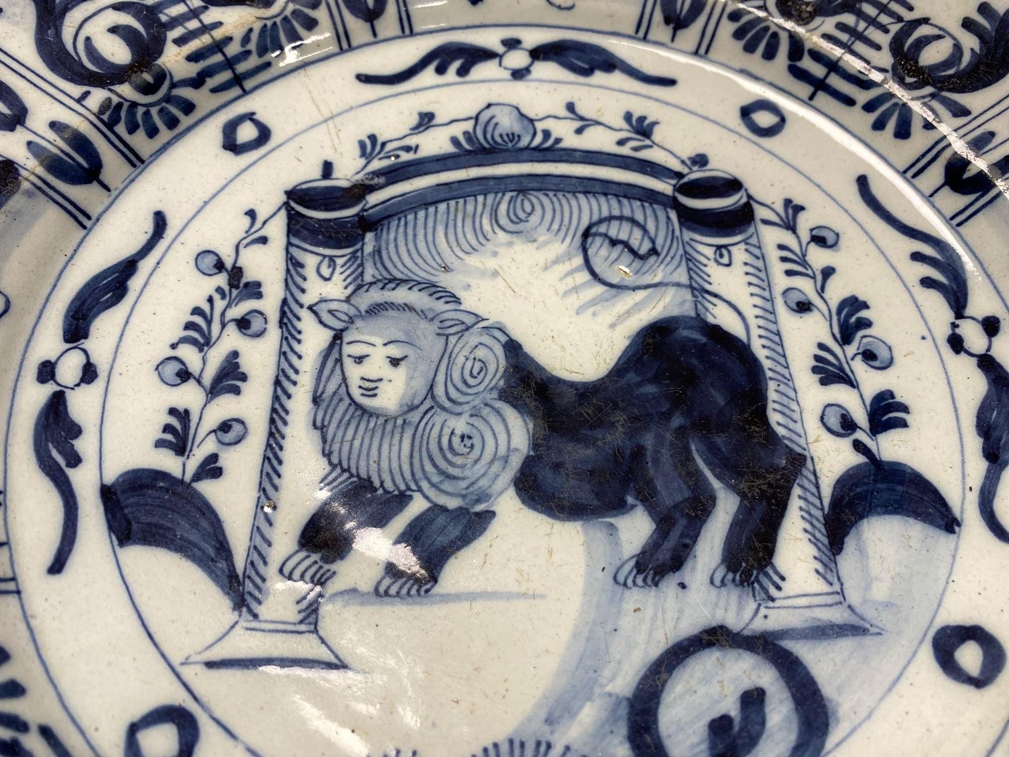 An 18th century Delft blue and white charger centred by a lion, with figural and foliate border, 32cm